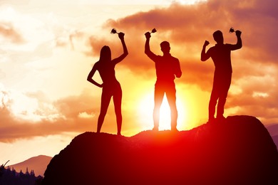 Image of Winners with trophy cups in mountains at sunrise