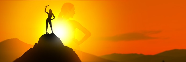 Winner with trophy cup in mountains at sunrise and silhouette of woman. Banner design