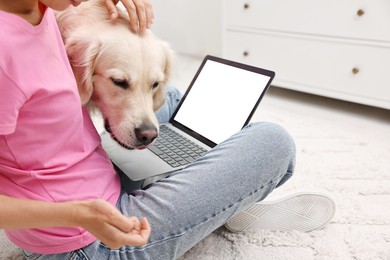 Photo of Online pet shop. Woman with laptop making order for cute Golden Retriever dog on rug at home, closeup