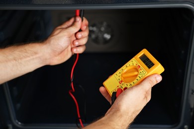 Repairman testing oven element with multimeter, closeup