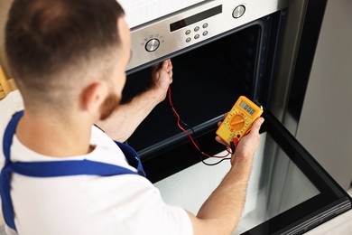 Repairman testing oven element with multimeter, above view