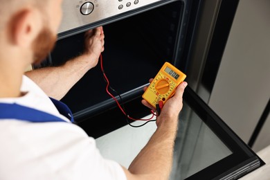 Repairman testing oven element with multimeter, closeup