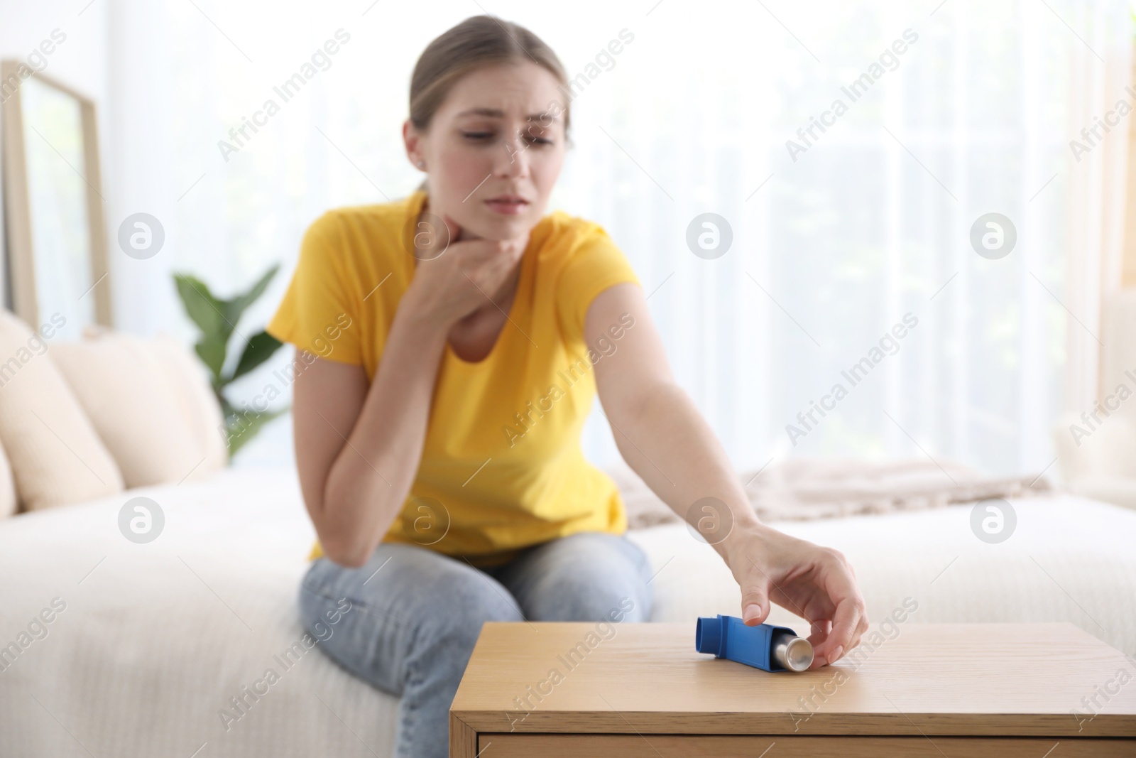 Photo of Young woman using asthma inhaler at home, selective focus