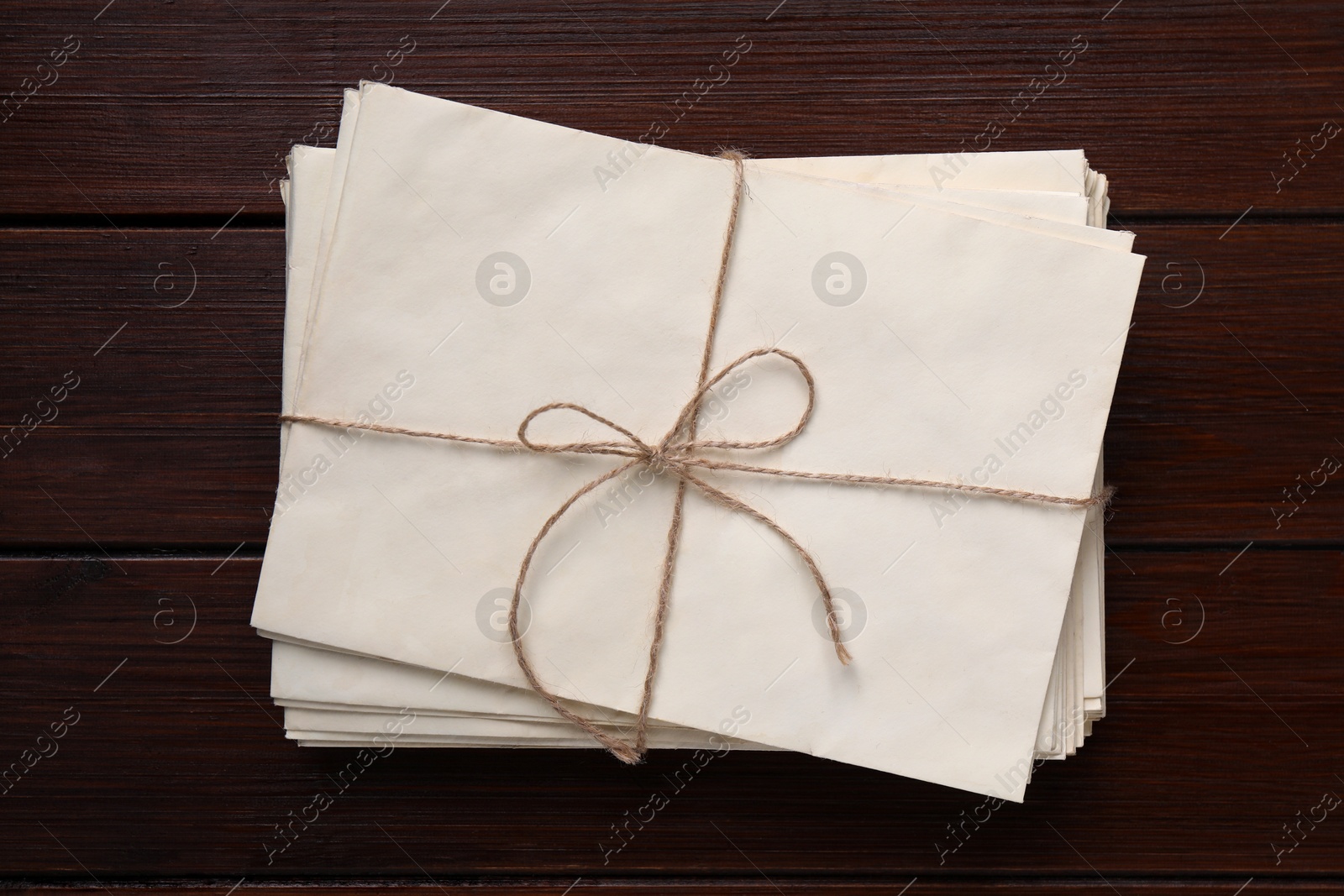 Photo of Stack of old letters tied with twine on wooden table, top view