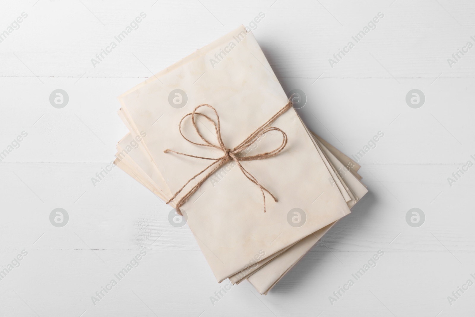 Photo of Stack of old letters tied with twine on white wooden table, top view