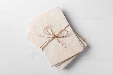 Stack of old letters tied with twine on white wooden table, top view