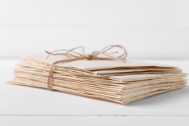 Photo of Stack of old letters tied with twine on white wooden table, closeup