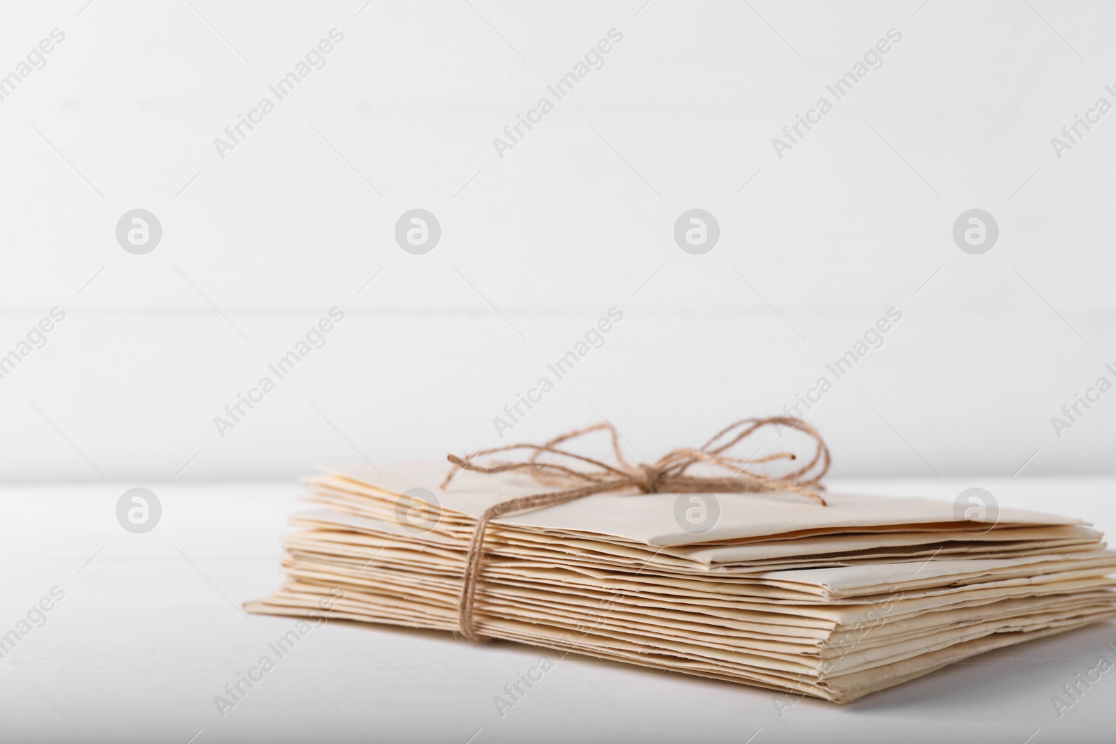 Photo of Stack of old letters tied with twine on white wooden table, closeup