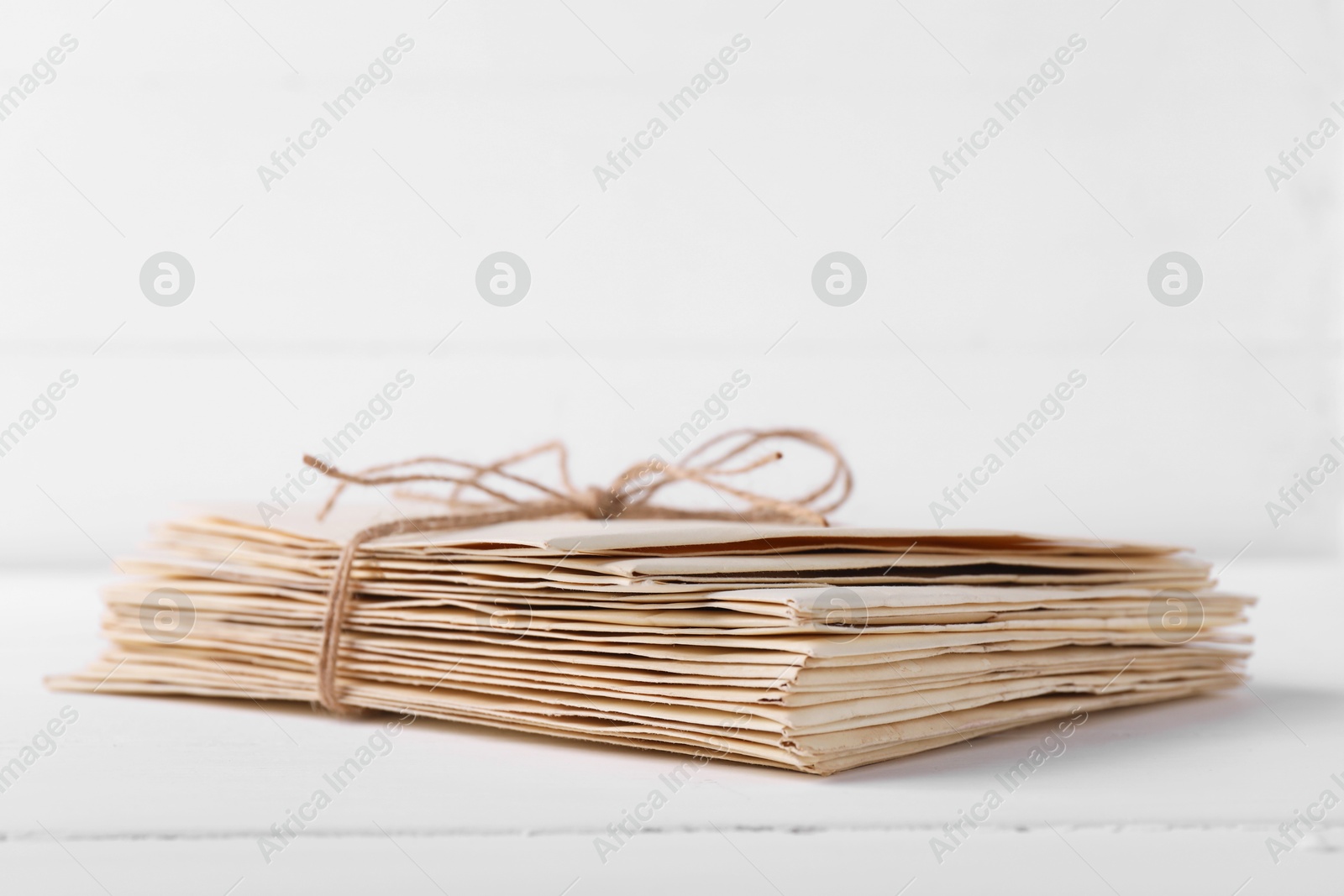 Photo of Stack of old letters tied with twine on white wooden table, closeup