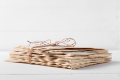 Photo of Stack of old letters tied with twine on white wooden table, closeup