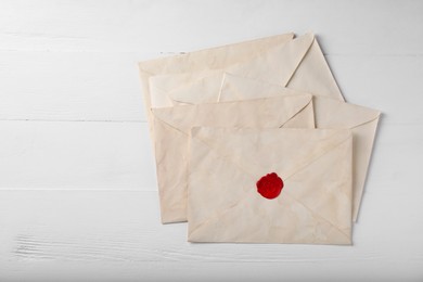 Photo of Old letter envelopes on white wooden table, top view. Space for text