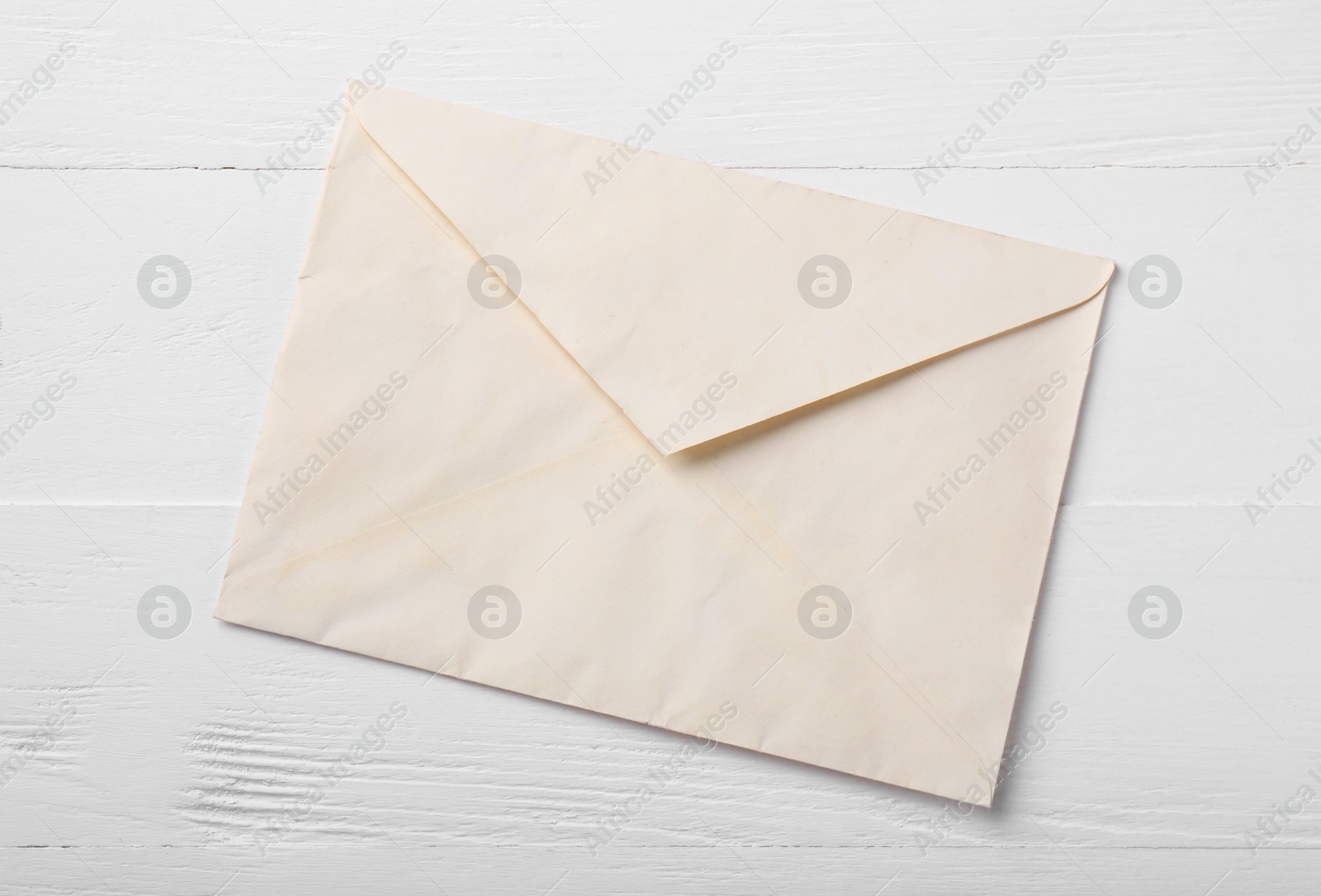 Photo of One old letter envelope on white wooden table, top view