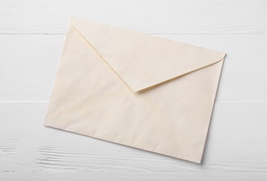 Photo of One old letter envelope on white wooden table, top view