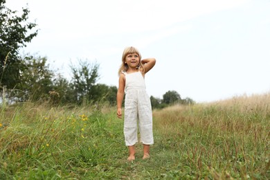 Photo of Cute little girl walking barefoot at meadow. Child enjoying beautiful nature