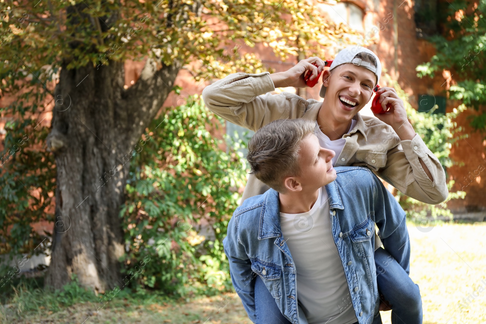 Photo of Happy brothers spending time together outdoors. Space for text