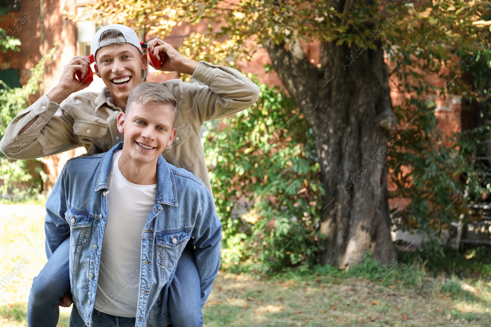 Photo of Happy brothers spending time together outdoors. Space for text