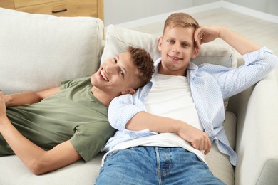 Happy brothers chilling on sofa at home