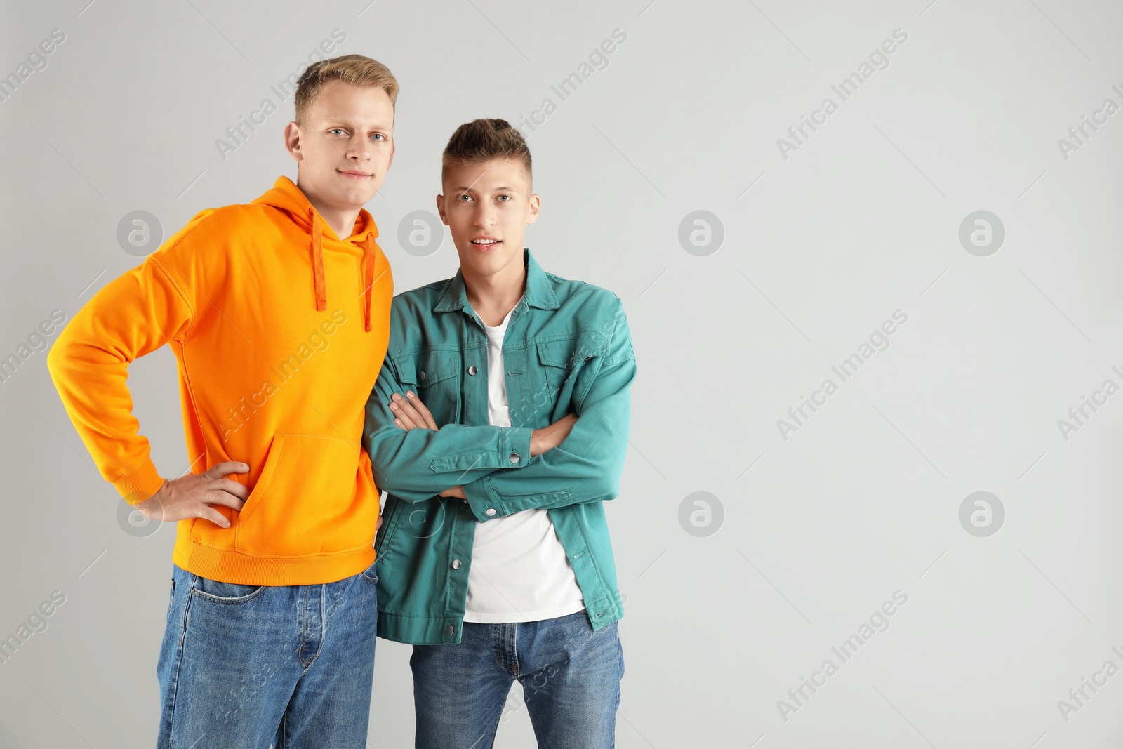 Photo of Two happy brothers posing on light background. Space for text