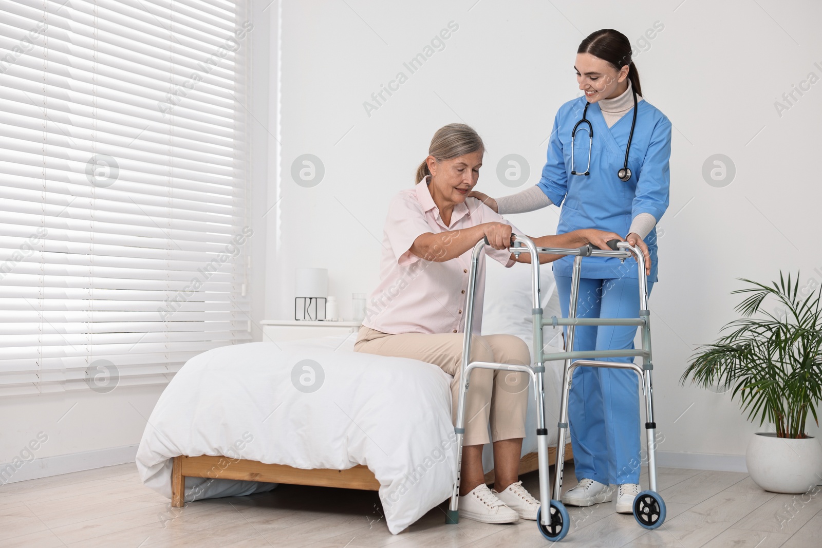 Photo of Nurse helping senior woman with walking frame in clinic