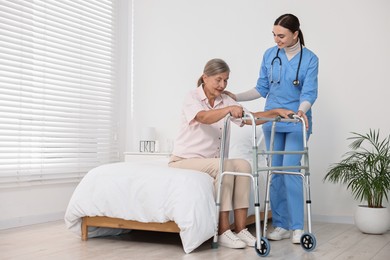 Nurse helping senior woman with walking frame in clinic