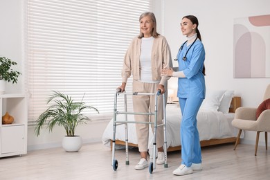 Photo of Nurse helping senior woman with walking frame in clinic