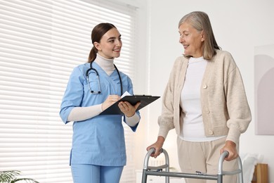 Photo of Nurse helping senior woman with walking frame in clinic