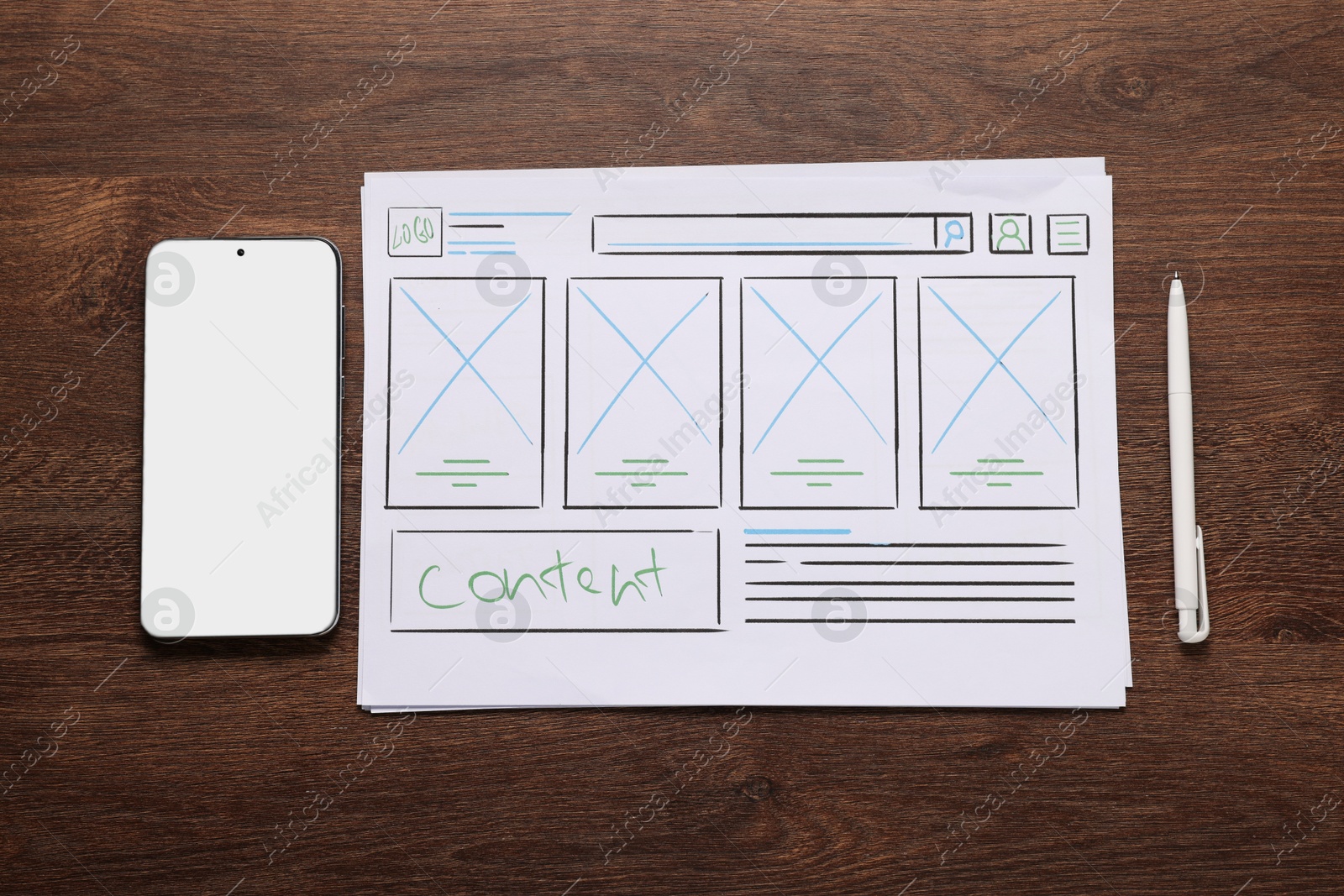 Photo of Developing UI design. Sketches of website wireframes, smartphone and pen on wooden table, top view