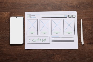 Developing UI design. Sketches of website wireframes, smartphone and pen on wooden table, top view