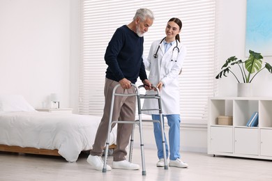 Doctor helping senior man with walking frame in clinic