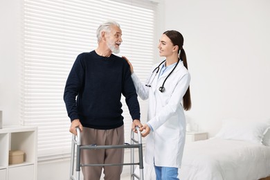 Doctor helping senior man with walking frame in clinic