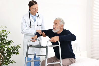 Doctor helping senior man with walking frame in clinic