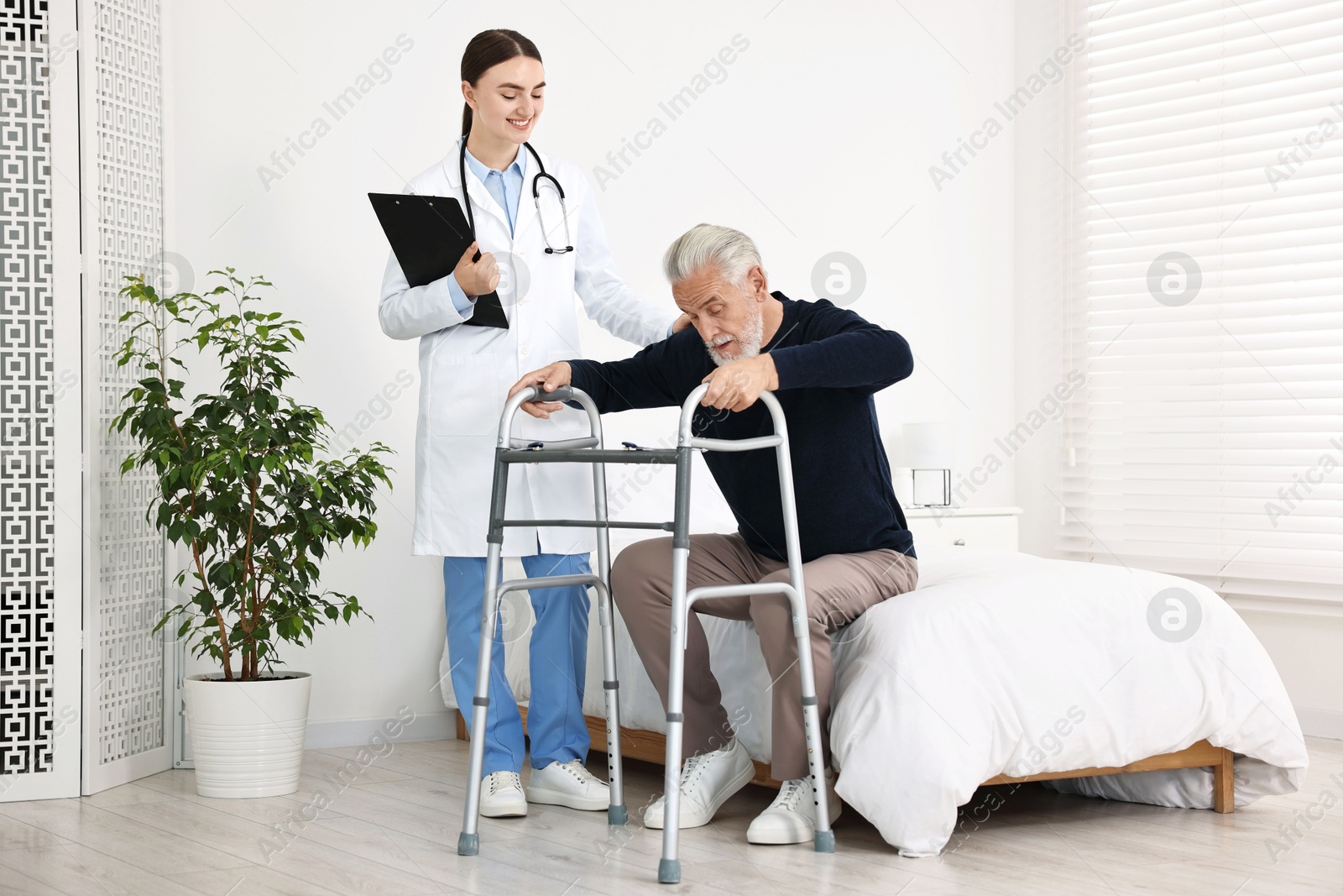 Photo of Doctor helping senior man with walking frame in clinic