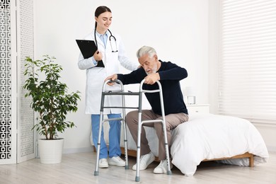 Doctor helping senior man with walking frame in clinic