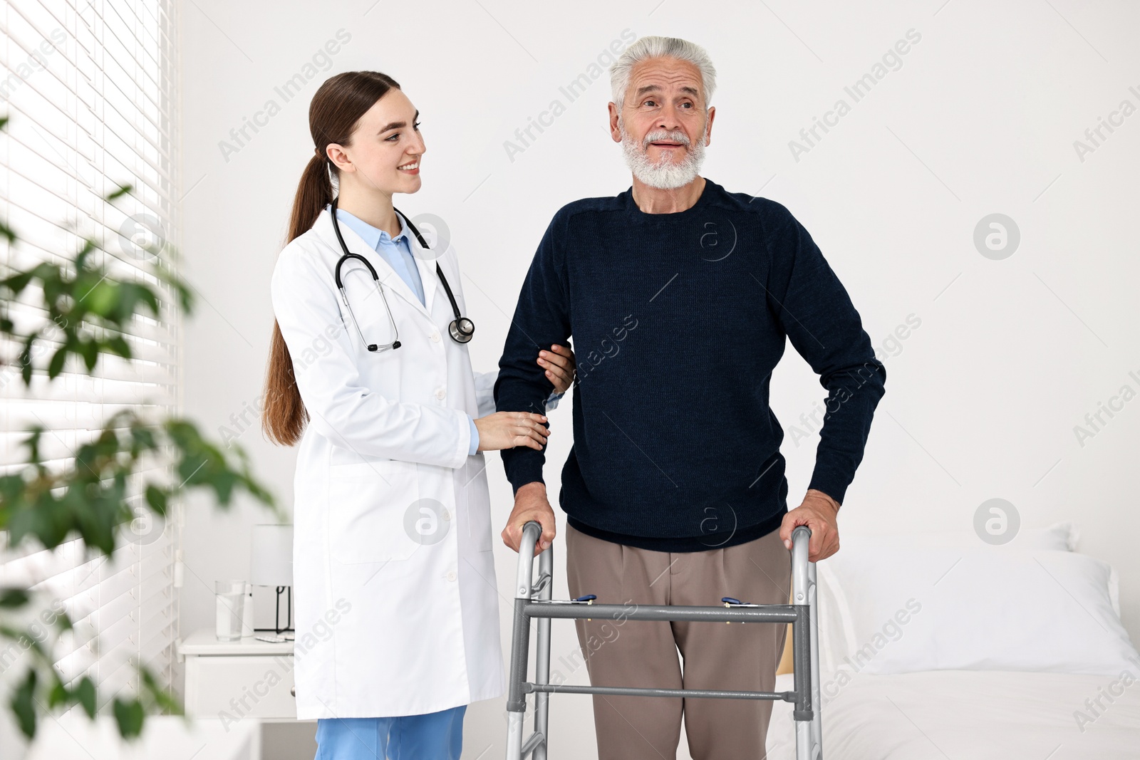 Photo of Doctor helping senior man with walking frame in clinic