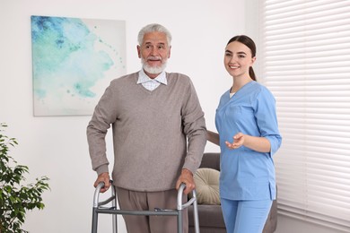 Nurse helping senior man with walking frame in clinic