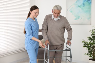 Photo of Nurse helping senior man with walking frame in clinic