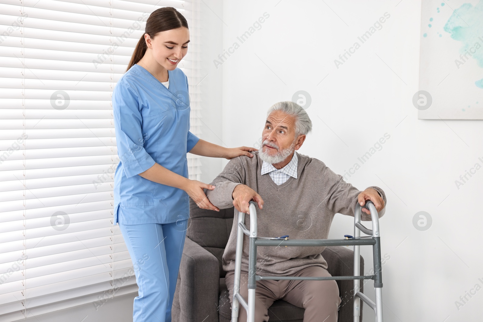 Photo of Nurse helping senior man with walking frame in clinic