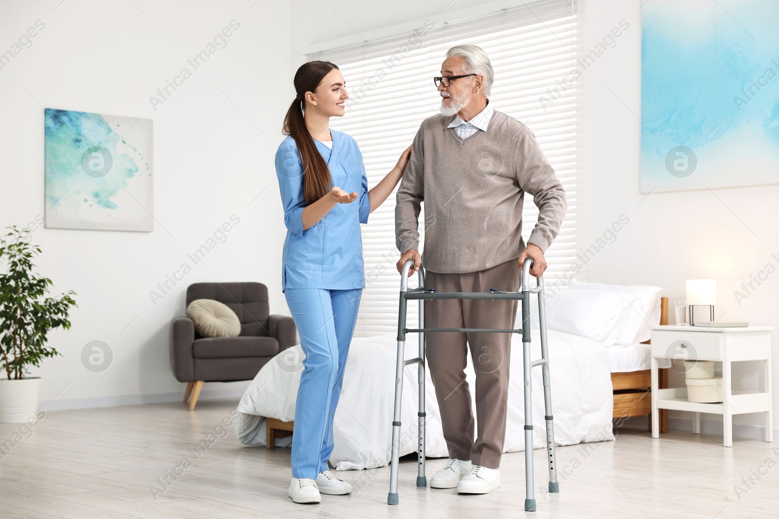 Photo of Nurse helping senior man with walking frame in clinic