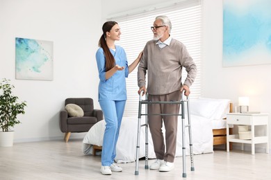 Nurse helping senior man with walking frame in clinic