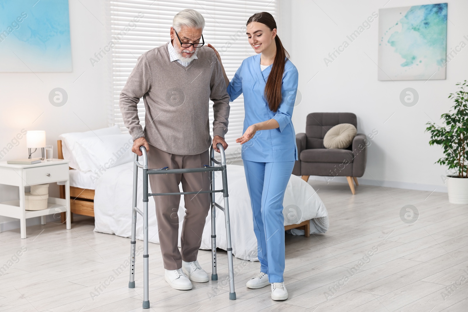 Photo of Nurse helping senior man with walking frame in clinic