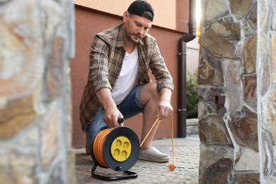 Photo of Man with extension cord reel in backyard