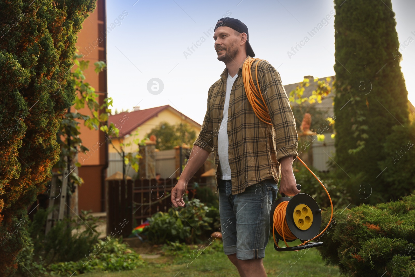 Photo of Man with extension cord reel in backyard