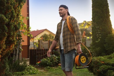 Man with extension cord reel in backyard