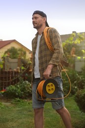 Man with extension cord reel in backyard