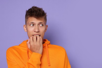 Portrait of scared young man on violet background, space for text