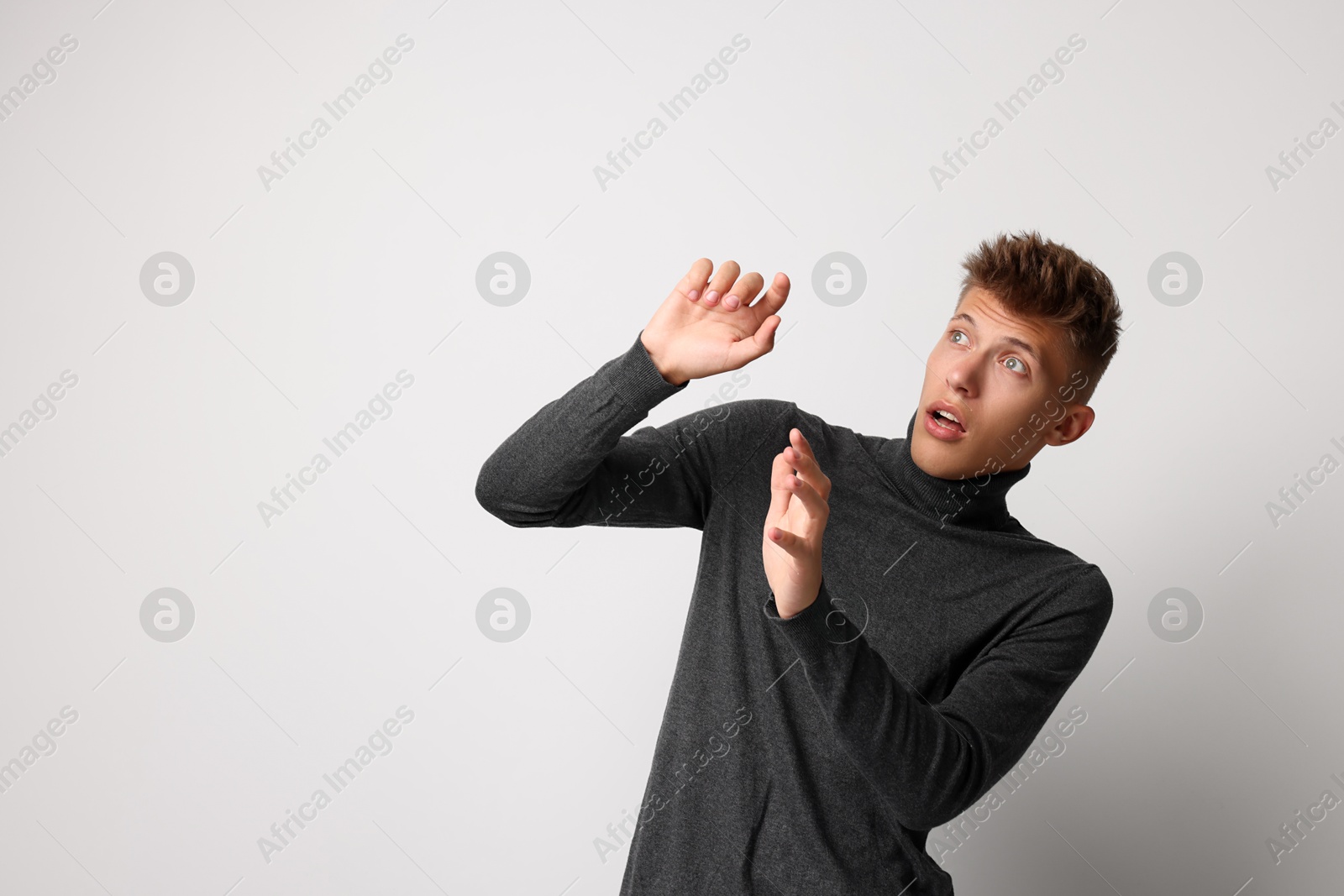 Photo of Portrait of scared young man on light background, space for text