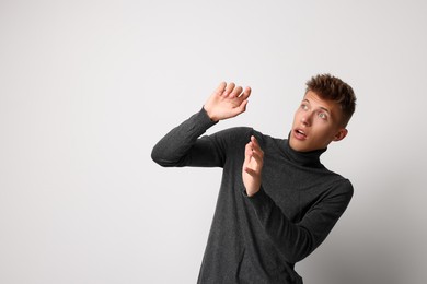 Portrait of scared young man on light background, space for text