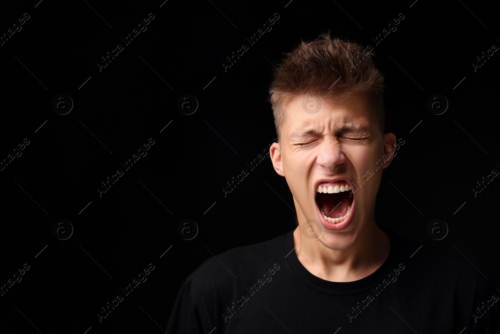 Photo of Portrait of scared young man on black background, space for text