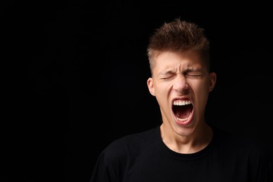 Photo of Portrait of scared young man on black background, space for text