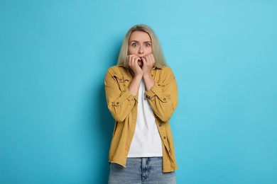 Portrait of scared woman on light blue background